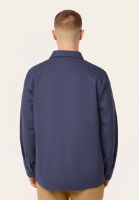 Marineblauwe knopsluiting overhemd met lange mouwen, gestructureerde stof, rechte pasvorm en een standaard kraag. Voorzien van knoopmanchetten.