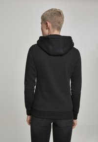 Black hoodie with a spacious hood, ribbed cuffs and hem, and smooth texture. Featured is a simple, functional design without patterns.