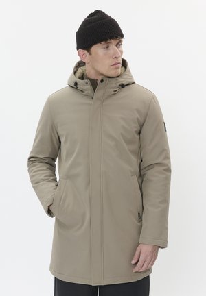 Khaki Parka-Jacke mit Kapuze, Reißverschluss und Seitentaschen. Glattes Material und verstellbare Kordeln an der Kapuze. Schwarze Strickmütze.