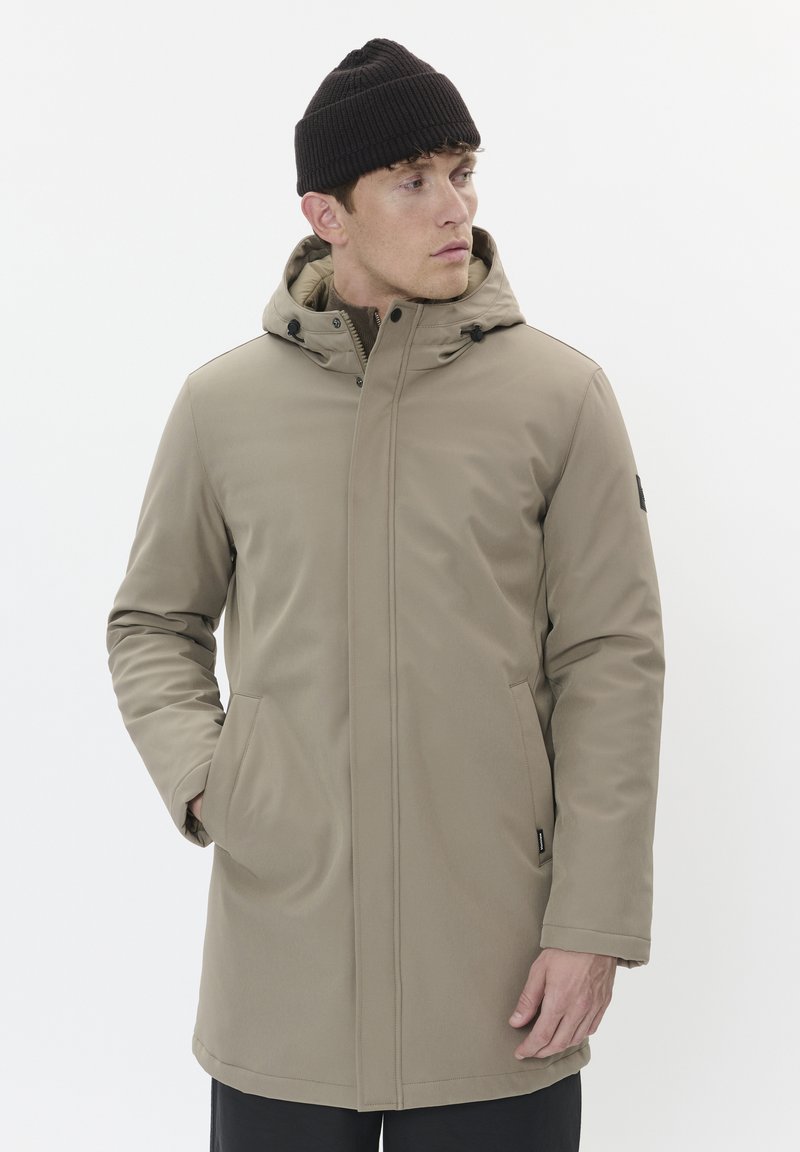 Khaki parka bunda s kapucňou, so zipsovým zapínaním a bočnými vreckami. Hladká tkanina a nastaviteľné šnúrky na kapucni. Čierna pletená čiapka.
