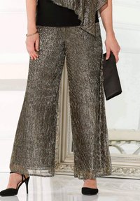 Metallisch plissierte, weit geschnittene Hose in glänzendem Bronze, mit glatter Textur. Getragen mit schwarzen High Heels und einer schwarzen Clutch.