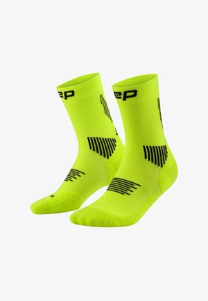 Calcetines deportivos en un brillante color amarillo-verde con patrones geométricos negros y la palabra parcial "step" cerca de la parte superior, mostrados sobre un fondo blanco.
