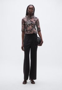 Floral-patterned top in shades of pink and grey, paired with high-waisted black trousers, and a small black handbag. Features round neckline and three-quarter sleeves.