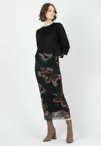 Svart kortväst i kombination med en midi kjol med blommönster i djupa färger, kompletterat med beige klackstövlar.