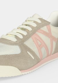 Baskets beige et roses en daim et mesh avec lacets blancs et logo "Armani Exchange" sur le côté.