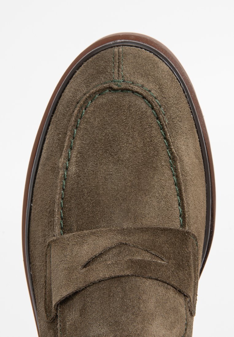 Scarpa mocassino in suede verde oliva con cuciture a contrasto e una fascia decorativa. Punta rotonda con una leggera lucentezza e suola in gomma marrone.