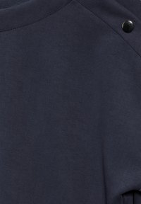 Námořnická modrá mikina z měkké, strukturované tkaniny s kulatým výstřihem a kovovými akcentovými knoflíky na rameni. Hladký, ležérní design.