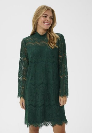 Vestido verde de encaje con mangas largas, cuello alto, patrones intrincados, dobladillo con forma de escalloped, textura translúcida y un diseño de corte holgado.