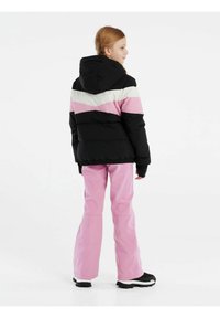 Doudoune noire avec des rayures horizontales roses et blanches, capuche et poignets élastiques ; accompagnée de pantalons roses et de bottes noires.