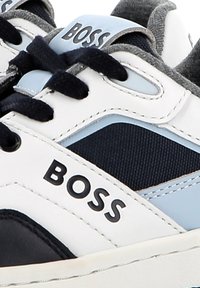 Baskets au design blanc, marine et bleu clair. Fabriquées en cuir et en tissu, avec des lacets ronds et un audacieux logo "BOSS" sur le côté.