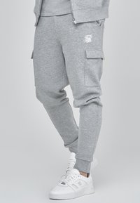 Graue Jogginghose aus einem weichen Baumwollmix, mit Cargo-Taschen, gerippten Bündchen und einem weißen Logodetail am Oberschenkel.