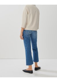 Beige top s tříčtvrtečními rukávy v kombinaci s modrými zkrácenými džínami a černými balerínami. Hladká látka s minimalistickým designem a bez viditelných vzorů.