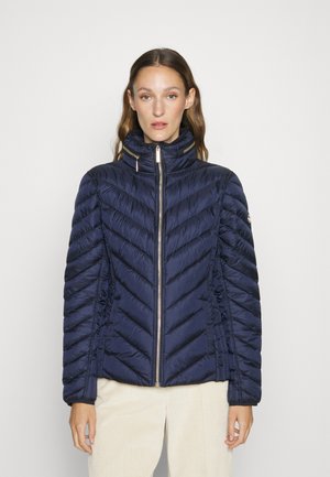 Chaqueta acolchada de color azul marino con patrón en zigzag, cuello alto, cierre frontal y detalles de fruncido en los lados. Acabado suave y brillante. Adecuada para el clima frío.