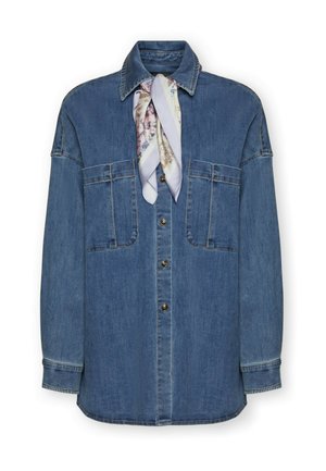 Džínová košile se zapínáním na knoflíky, dvěma velkými náprsními kapsami a viskózovým šátkem s vzorem uvázaným kolem límce na bílém pozadí.