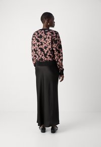 Črna cvetlična jopica z rožnatimi vzorci, z ribastimi manšetami in robom, v kombinaciji z dolga črna satenasta krila in črne čevlje. Gledano od zadaj.