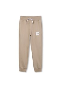 Beige sweatpants met elastische tailleband en trekkoord, voorzien van het witte "DKNY" logo op de linker dij, met cuffs aan de enkels en een gladde textuur.