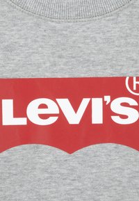 Grå bomullssweatshirt med en stor rød Levi's-logo med hvit tekst og en buet grafisk design på den nedre delen.