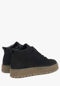 Czarne zamszowe botki za kostkę o gładkiej fakturze, z zaokrąglonym noskiem i wyściełanym kołnierzem. Posiadają chunky brązową gumową podeszwę z teksturowanym gripem.