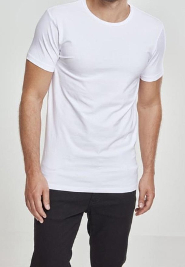 Homme portant un t-shirt blanc uni ajusté à manches courtes et un pantalon noir, debout devant un fond neutre.