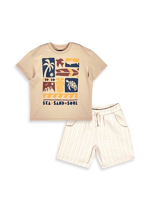Beige t-shirt med korte ærmer med tropiske prints og teksten "Sea Sand Soul", kombineret med hvide shorts med tynde gule striber og snøre i taljen.