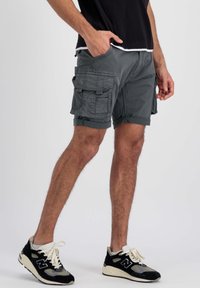 Sive cargo kratke hlače s višestrukim džepovima, uzdužnim rubovima i laganom tkaninom. Uparene s crno-sivim New Balance tenisicama.