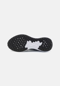 La suola della scarpa Nike presenta un design in gomma nera testurizzata con un'area bianca che mostra il logo. Il motivo include forme ovali e circolari.