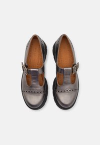 Grey leather shoes with a rounded toe, T-strap design, and decorative perforations, paired with a black rubber sole and buckle detail.