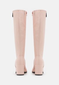 Knöchelhohe, rosa Kunstlederstiefel mit Blockabsätzen, Reißverschlüssen an der Rückseite und vertikalen Nahtdetails entlang des Schafts. Glatte Textur.