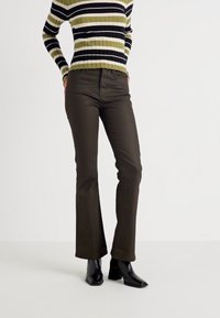 Ruske levele hameet, kjol är gjord av ett slätt tyg, tillsammans med en svart och grön randig ribbad tröja. Svarta ankelstövlar fulländar outfiten.