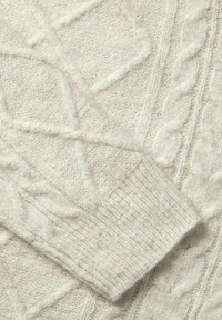 Pullover lavorato a maglia di un beige chiaro, con motivi a treccia e diamante testurizzati. Il polsino a costine aggiunge un tocco di dettaglio al morbido e soffice tessuto.