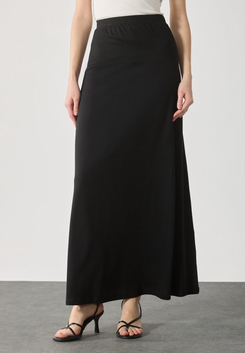 Zwarte, enkel-lange rok gemaakt van zachte, rekbare stof met een elastische tailleband. Heeft een gladde textuur en een eenvoudig, ononderbroken ontwerp.