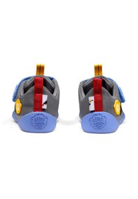 Zapatos de tela grises con suelas azules, acentos rojos y amarillos, y correas de velcro. Presentan parches de animales y una marca en el talón.