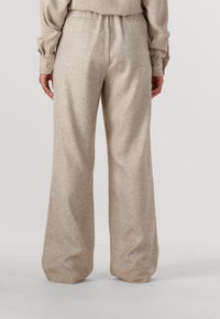 Beige wijdvallende broeken van textuurstof, met een hoge tailleband en twee achterzakken. Het materiaal heeft een subtiel visgraatpatroon.