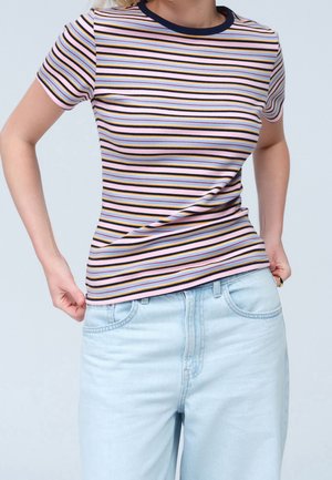 Person wearing a fitted, short-sleeve, ribbed top with horizontal stripes in pastel and dark colors, paired with light blue denim jeans.