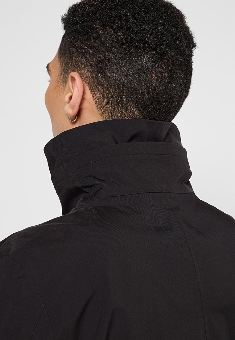 Schwarze wasserdichte Jacke mit hohem Kragen, glatter Textur und minimalistischem Design. Merkmale sind dezente Nahtdetails und keine sichtbare Hardware.
