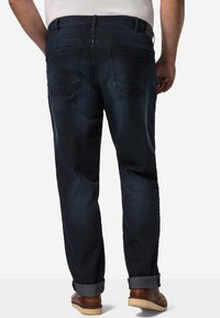 Jeans de mezclilla azul oscuro con corte recto, puños enrollados y dos bolsillos traseros. Presenta detalles de costura y un acabado texturizado.