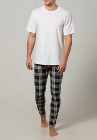 Weißes Baumwoll-T-Shirt kombiniert mit schwarz-grau karierten Leggings. Die Leggings haben eine enge Passform und eine glatte Textur.