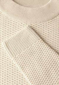 Licht beige gebreide trui met een textuurpatroon en een ribgebreide ronde halslijn en mouwen voor een snug fit. Zacht en comfortabel materiaal.