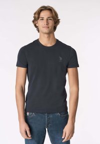 Maglietta blu navy a maniche corte in cotone, con scollo rotondo e un sottile logo USPA sul petto a sinistra.