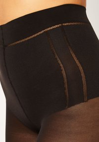 Collant neri a vita alta con una texture liscia, caratterizzati da una cintura larga e una sottile cucitura marrone lungo i lati.