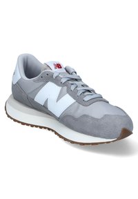 Zapatilla gris que combina ante texturizado y tela suave, con un destacado logo 'N' blanco, cordones grises y suela clara.