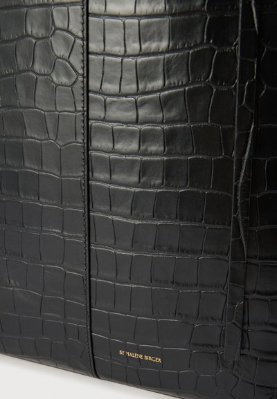 Μαύρη τσάντα χειρός με υφή κροκόδειλου και χρυσό λογότυπο "By Malene Birger", με ορατή ραφή και λεία επιφάνεια.