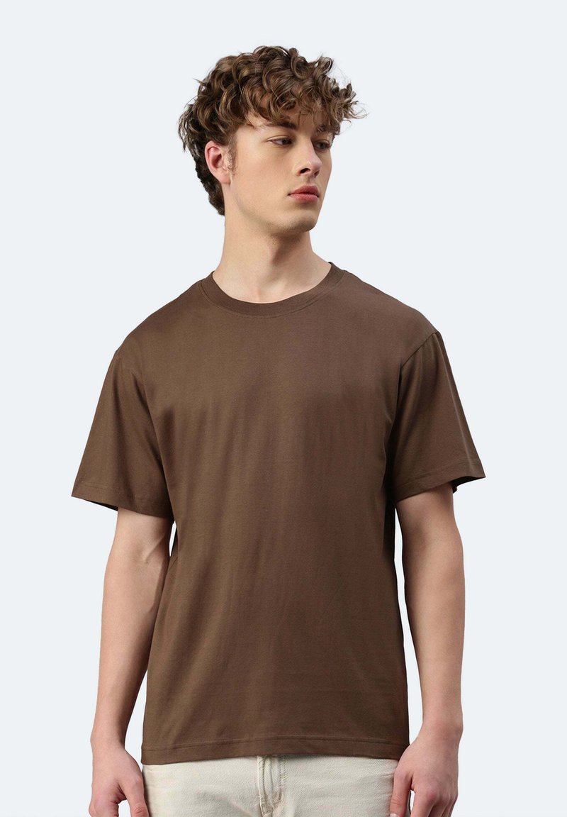 T-shirt in cotone marrone con scollatura a girocollo e maniche corte. Il tessuto appare morbido con un design semplice, senza motivi o accenti visibili.