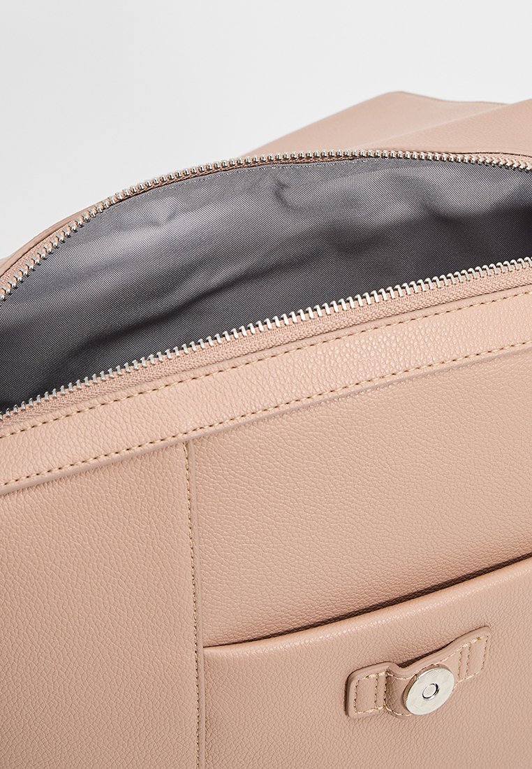 Helle rosa Lederhandtasche mit silbernem Reißverschluss, ausgestattet mit einem grauen Innenfutter. Beinhaltet eine Fronttasche mit einem Knopfverschluss.