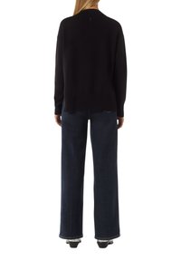 Black knit sweater with long sleeves, relaxed fit, and a back slit. Paired with high-waisted, wide-leg dark blue jeans.