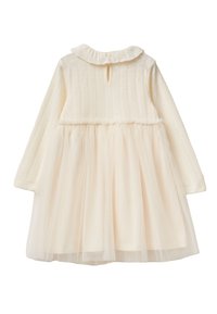 Vestido de color crema con un corsé texturizado, cuello con volantes y falda de tul transparente. Cierre de botones en la parte posterior con un detalle de corte circular.