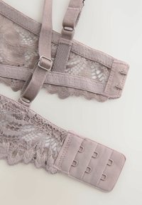 Lace bralette pehmeas maavärvides, reguleeritavate rihmadega, laineliste servadega, konksu ja silmuse sulgemisega ning keeruka pitsist detailiga.