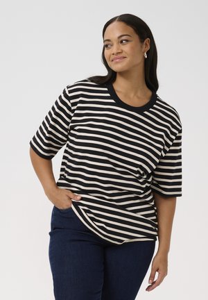 Maglietta a righe con righe orizzontali nere e crema, scollatura rotonda, maniche corte e vestibilità rilassata, abbinata a jeans blu scuro.
