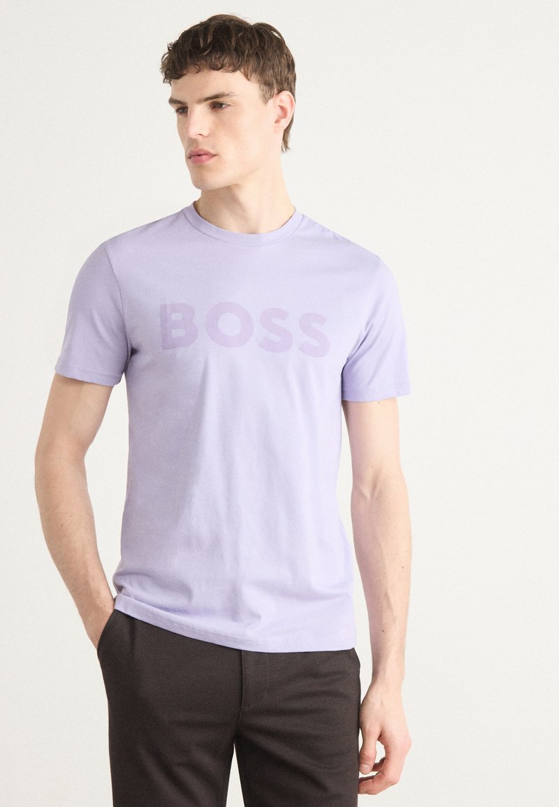 T-shirt en coton lavande avec des manches courtes et un logo "BOSS" audacieux, légèrement plus foncé, à l'avant. Design simple et ajusté.