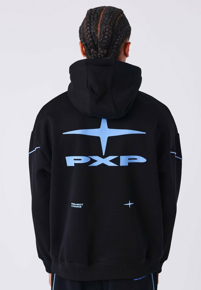 Persona con treccine a cornrow indossa una felpa nera con un grande logo blu "PXP", forme di stella e il testo "Project X Paris" sulla schiena.